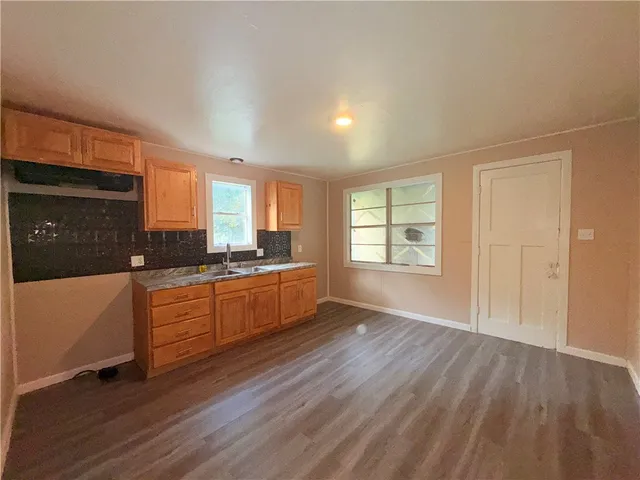 a large kitchen with cabinets wooden floor and a window