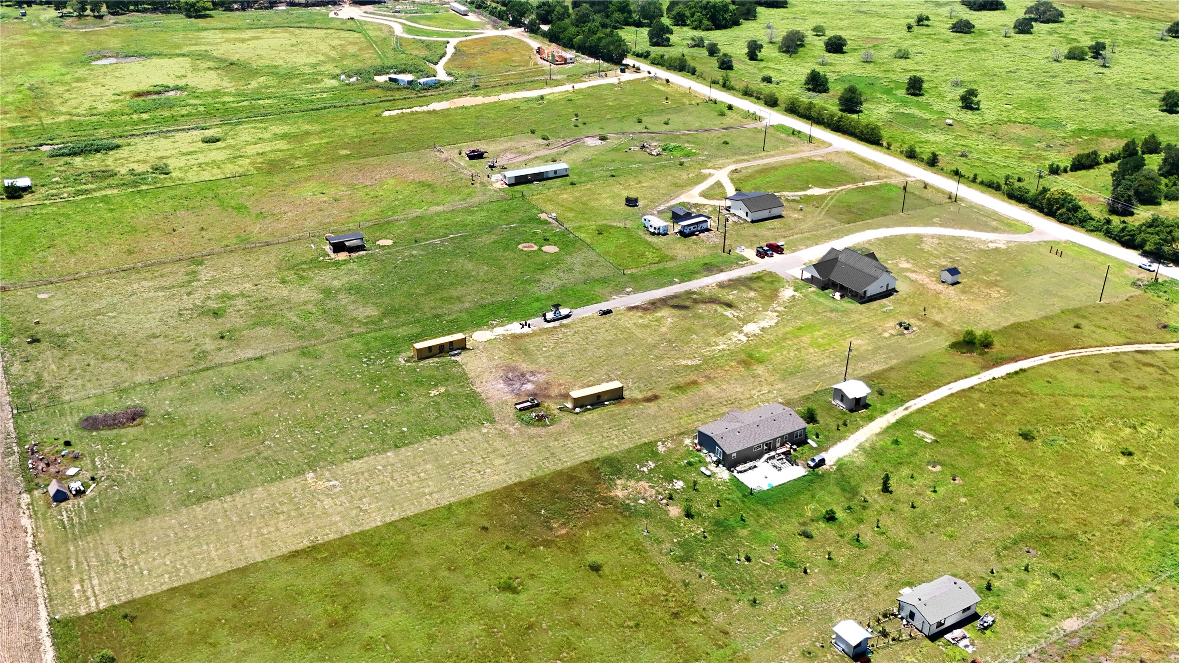 2889 Old McMahan Road Lockhart, TX 78644 - Photo 33 of 33 An aerial perspective reveals a vast rural landscape with several homes and structures nestled amidst verdant fields.