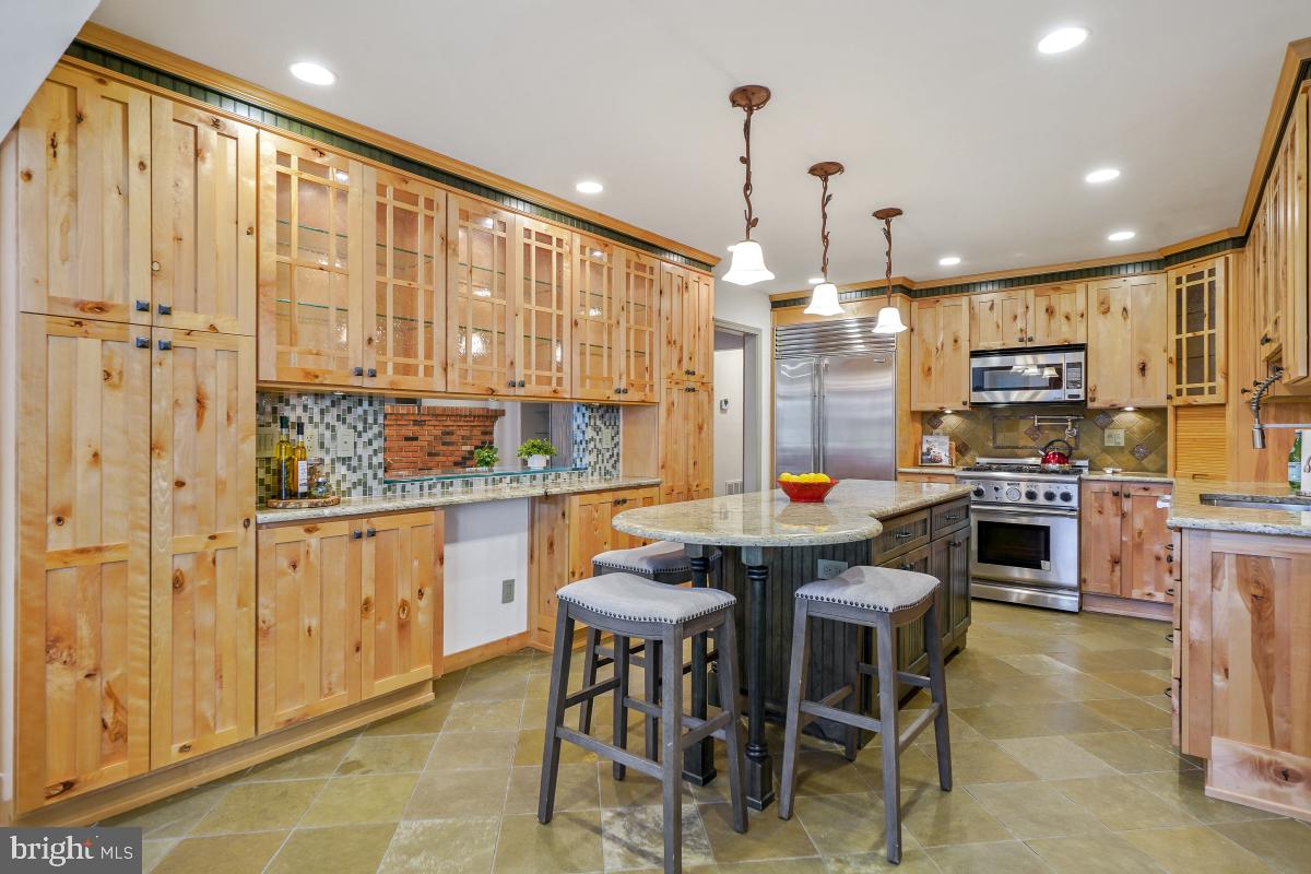9804 Korman Court Potomac, MD 20854 - Photo 16 of 66 a kitchen with stainless steel appliances kitchen island granite countertop a stove a sink a dining table and chairs