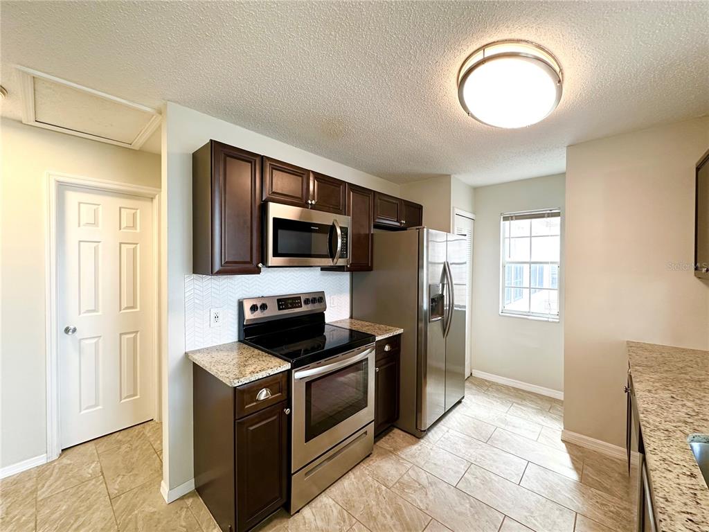 654 Roaring Drive, Unit 228 Altamonte Springs, FL 32714 - Photo 16 of 37 a kitchen with stainless steel appliances granite countertop a stove a sink and a refrigerator