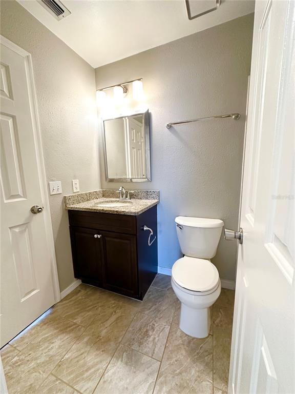 654 Roaring Drive, Unit 228 Altamonte Springs, FL 32714 - Photo 29 of 37 a bathroom with a granite countertop toilet a sink and a mirror