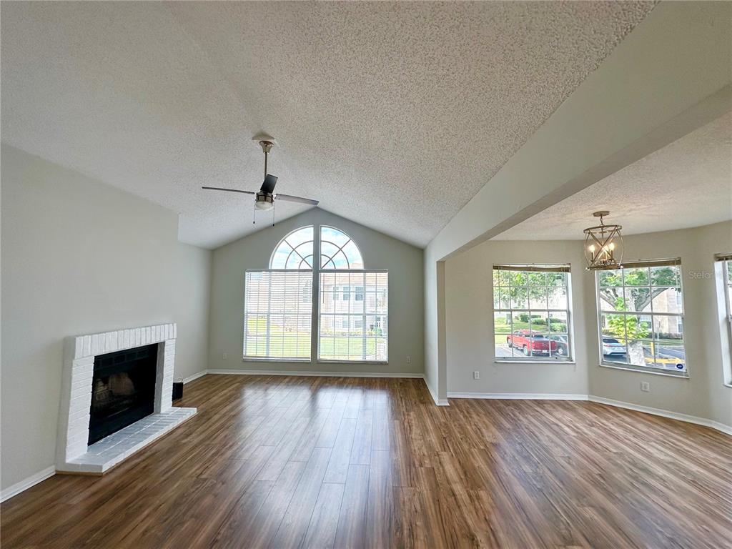 654 Roaring Drive, Unit 228 Altamonte Springs, FL 32714 - Photo 3 of 37 an empty room with wooden floor fireplace and windows