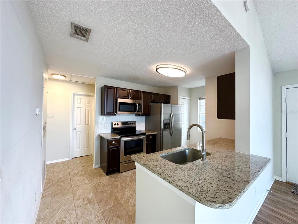 654 Roaring Drive, Unit 228 Altamonte Springs, FL 32714 - Photo 4 of 37 a kitchen with stainless steel appliances granite countertop a sink stove and refrigerator