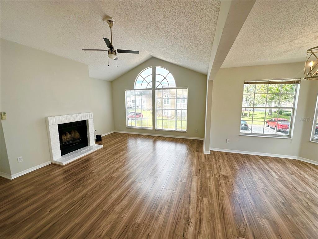 654 Roaring Drive, Unit 228 Altamonte Springs, FL 32714 - Photo 5 of 37 an empty room with wooden floor fireplace and windows
