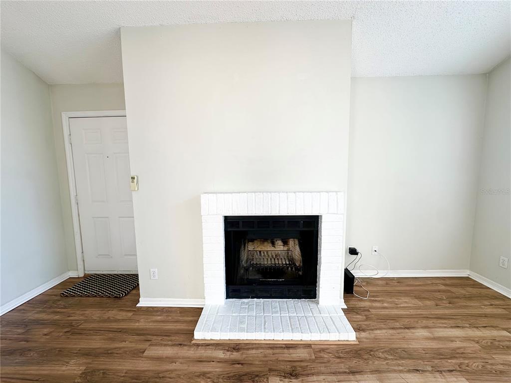 654 Roaring Drive, Unit 228 Altamonte Springs, FL 32714 - Photo 6 of 37 a view of an empty room with wooden floor and a fireplace