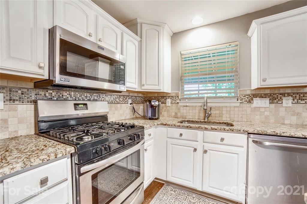11145 Carver Pond Road Charlotte, NC 28269 - Photo 7 of 30 a kitchen with granite countertop a stove sink and microwave