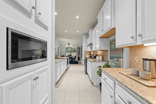 a large kitchen with granite countertop lots of counter space and stainless steel appliances