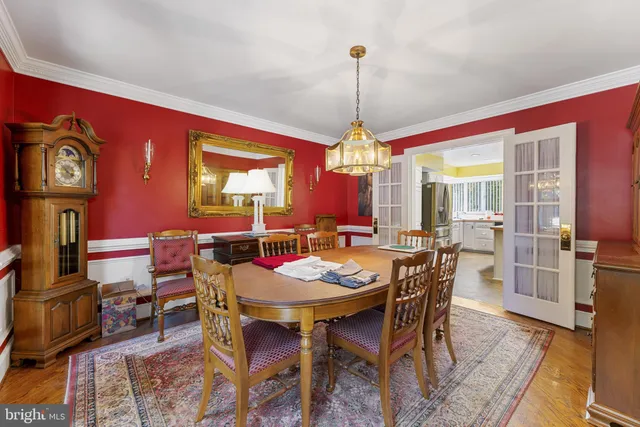 a view of a dining room and livingroom with furniture wooden floor a rug a painting and a chandelier