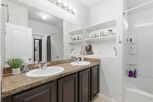 a bathroom with a granite countertop sink a mirror and a shower