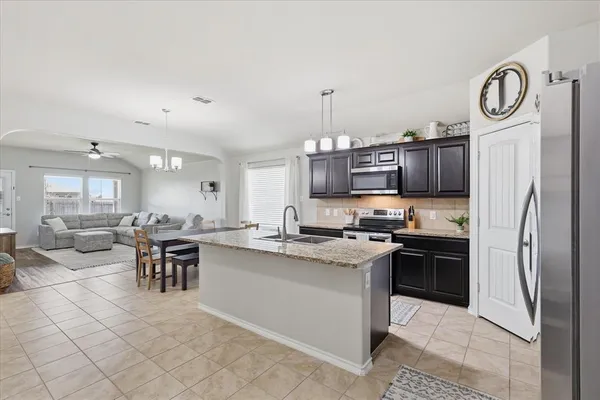 a kitchen with stainless steel appliances granite countertop a stove top oven a sink dishwasher a dining table and chairs with wooden floor