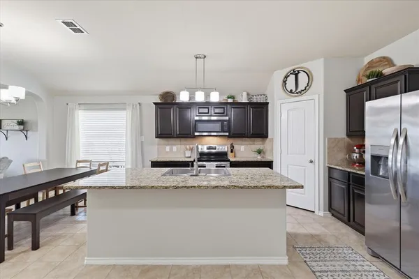 a large kitchen with stainless steel appliances granite countertop a sink a stove and a refrigerator