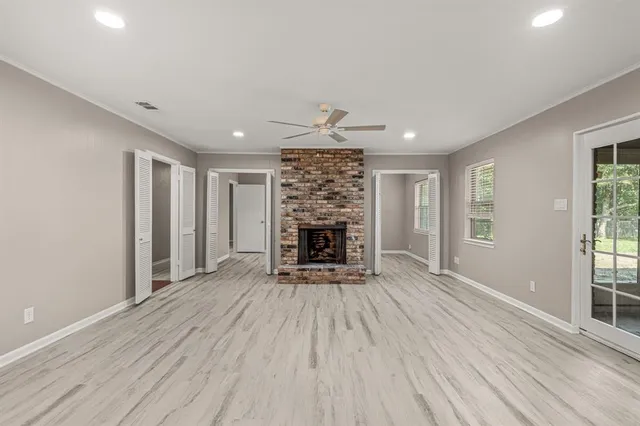 a view of an empty room with wooden floor fireplace and a window