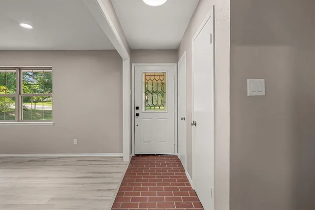 a view of a hallway with wooden floor and a window