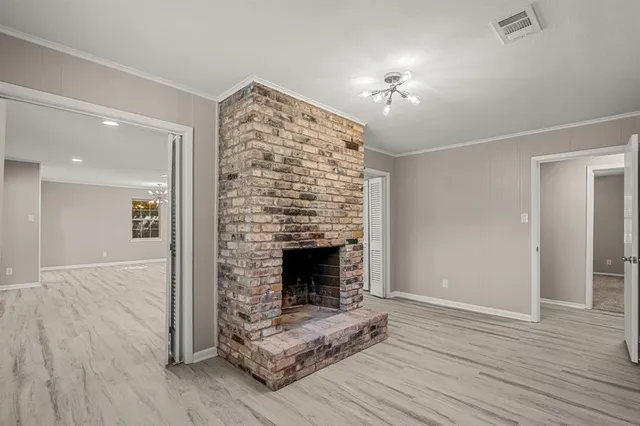 a view of an empty room with wooden floor fireplace and a window