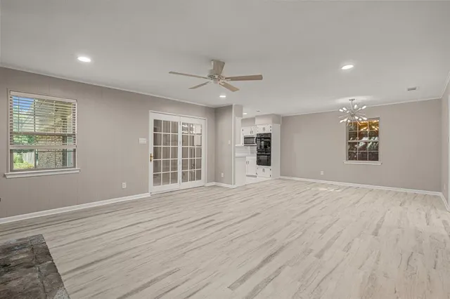 a view of an empty room with a window and a kitchen