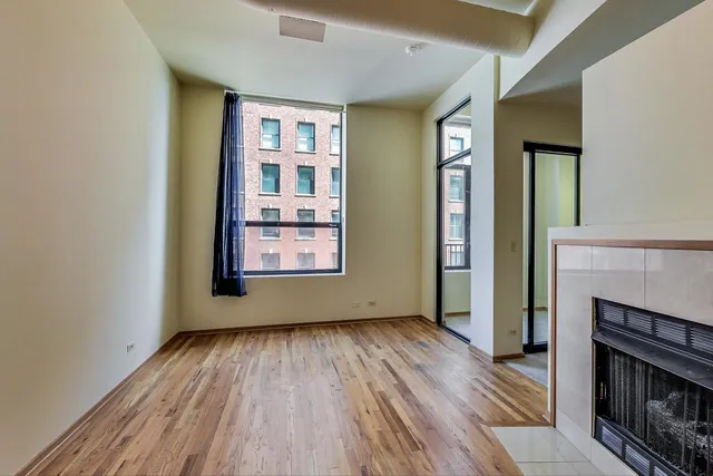 an empty room with windows and fireplace