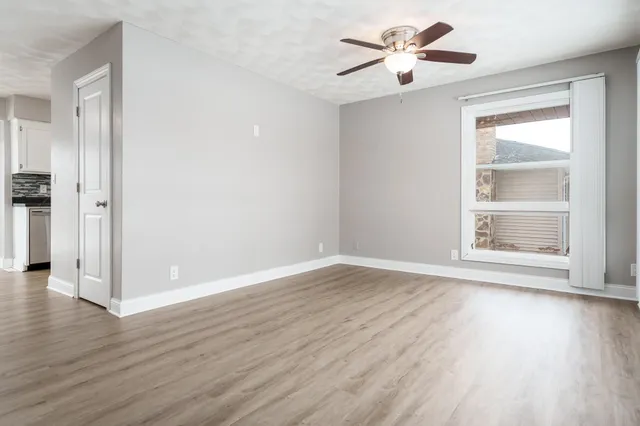 an empty room with wooden floor and windows
