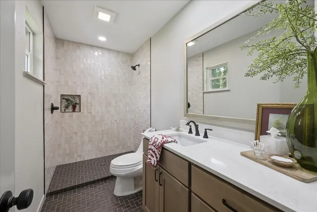 a bathroom with a granite countertop toilet a sink and a mirror