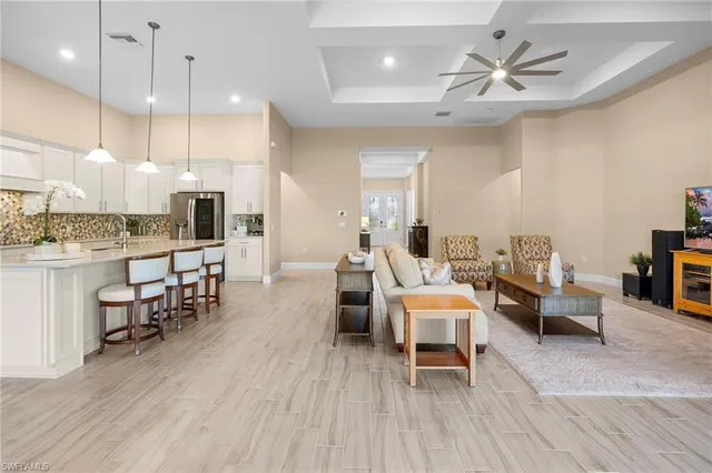 a living room with furniture kitchen view and a wooden floor