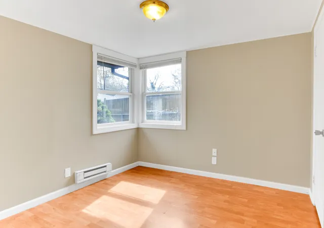 a view of an empty room with window and wooden floor