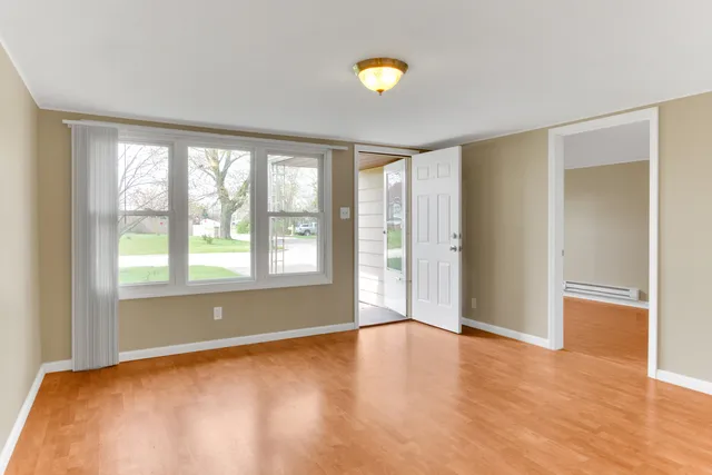 an empty room with wooden floor and windows