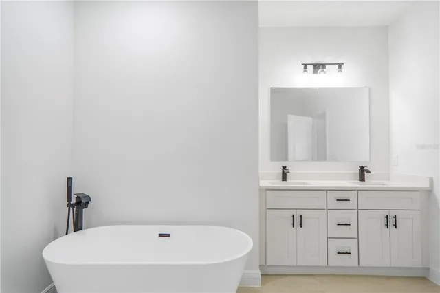 a bathroom with a white tub a sink and mirror