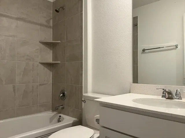 a bathroom with a granite countertop sink mirror toilet and bathtub