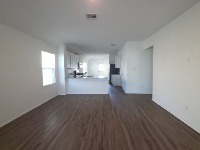 a view of empty room with wooden floor and window