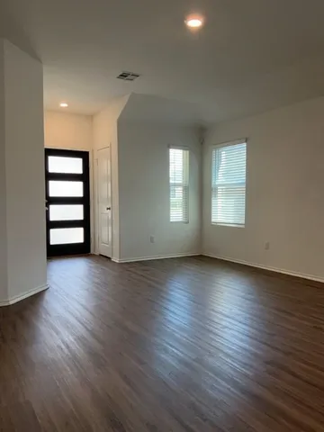 an empty room with wooden floor and window