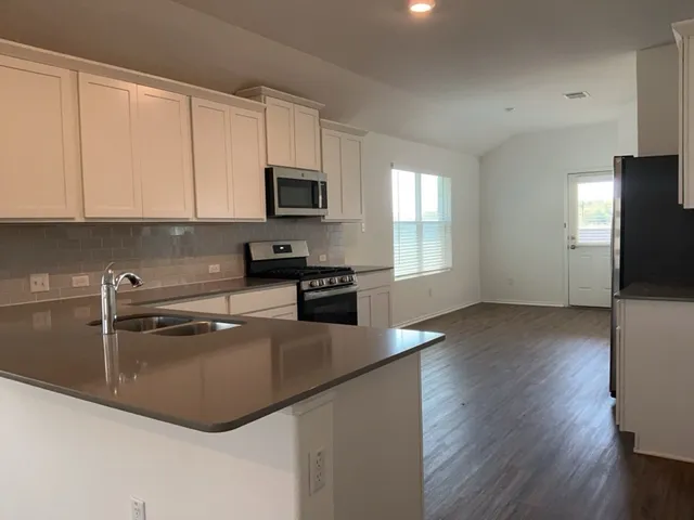 a kitchen with stainless steel appliances granite countertop a sink a stove top oven a counter space and cabinets