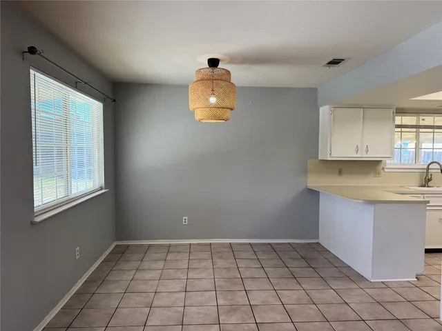 a view of kitchen with granite countertop white cabinets and window