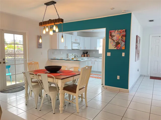 a kitchen with stainless steel appliances granite countertop a sink a stove a refrigerator a dining table and chairs