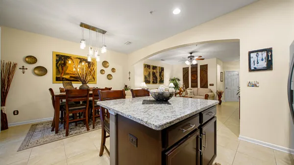 a view of kitchen island with granite countertop dining table chairs and refrigerator