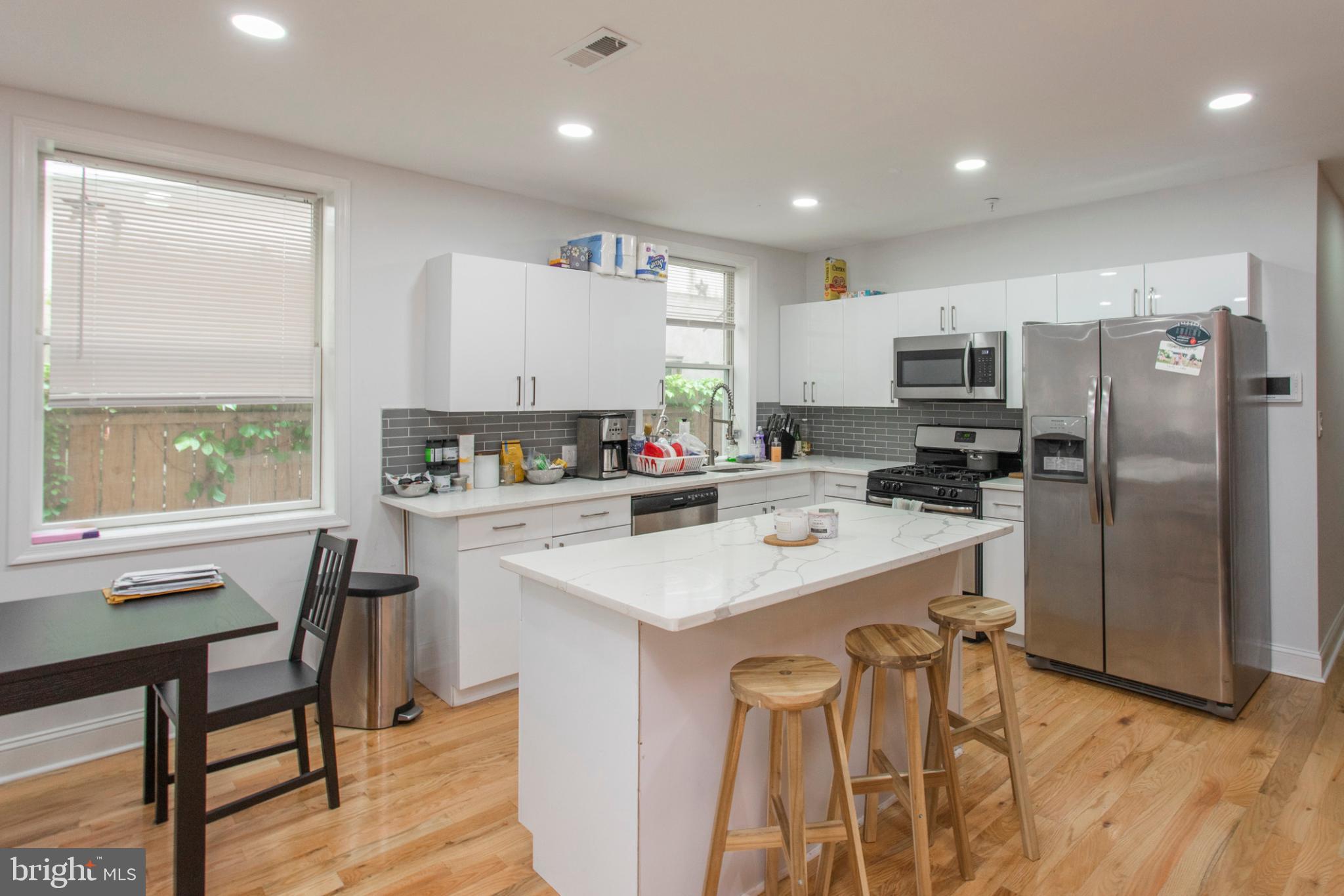 1629 Wallace Street, Unit 1R Philadelphia, PA 19130 - Photo 9 of 22 a kitchen with a refrigerator a stove a sink and a dining table with wooden floor