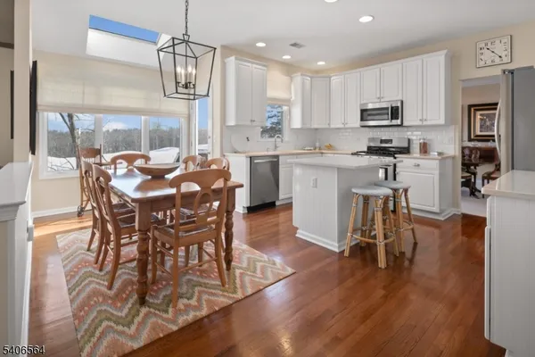 a kitchen with stainless steel appliances granite countertop a dining table chairs refrigerator and microwave