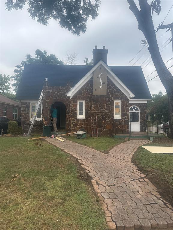 View of front of house featuring stone siding, a front lawn, and a chimney