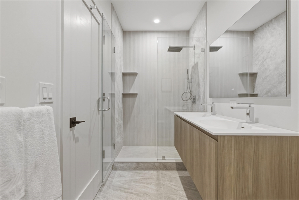 118 B Street, Unit 406 Boston, MA 02127 - Photo 5 of 9 a bathroom with a double vanity sink mirror and shower
