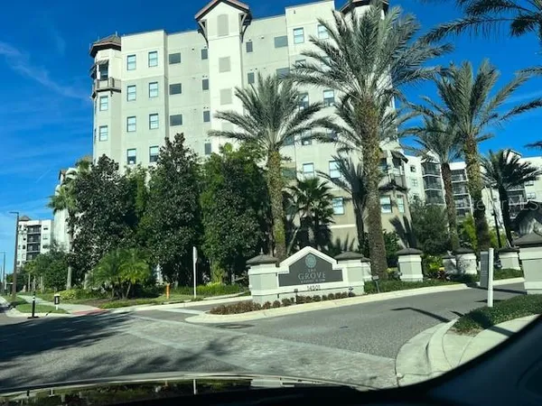 a view of a white house with a yard and palm trees