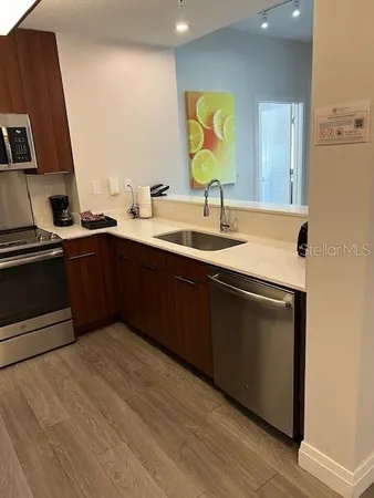 a kitchen with a sink and a stove with wooden floor
