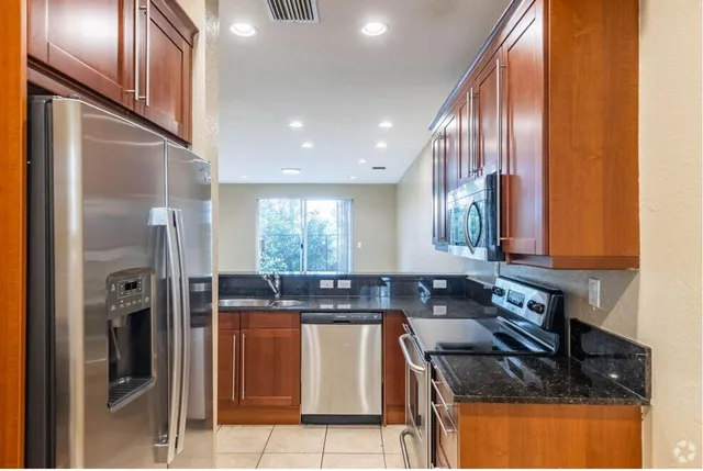 a kitchen with stainless steel appliances granite countertop a refrigerator a sink a stove and island