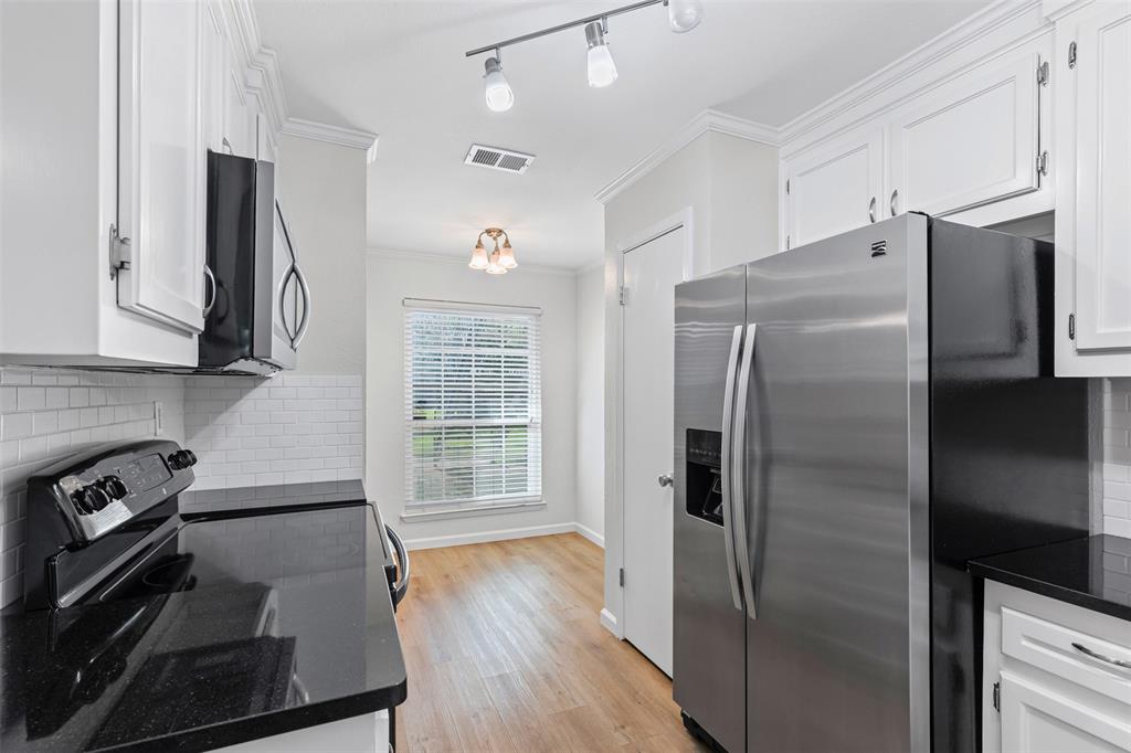 5981 Arapaho Road, Unit 703 Dallas, TX 75248 - Photo 6 of 19 Kitchen featuring appliances with stainless steel finishes, ornamental molding, white cabinets, and decorative backsplash