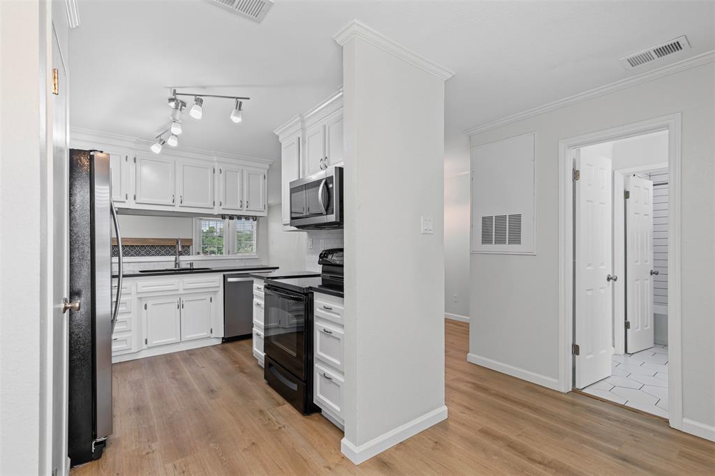 5981 Arapaho Road, Unit 703 Dallas, TX 75248 - Photo 7 of 19 Kitchen featuring appliances with stainless steel finishes, white cabinetry, dark countertops, light wood-style floors, and backsplash