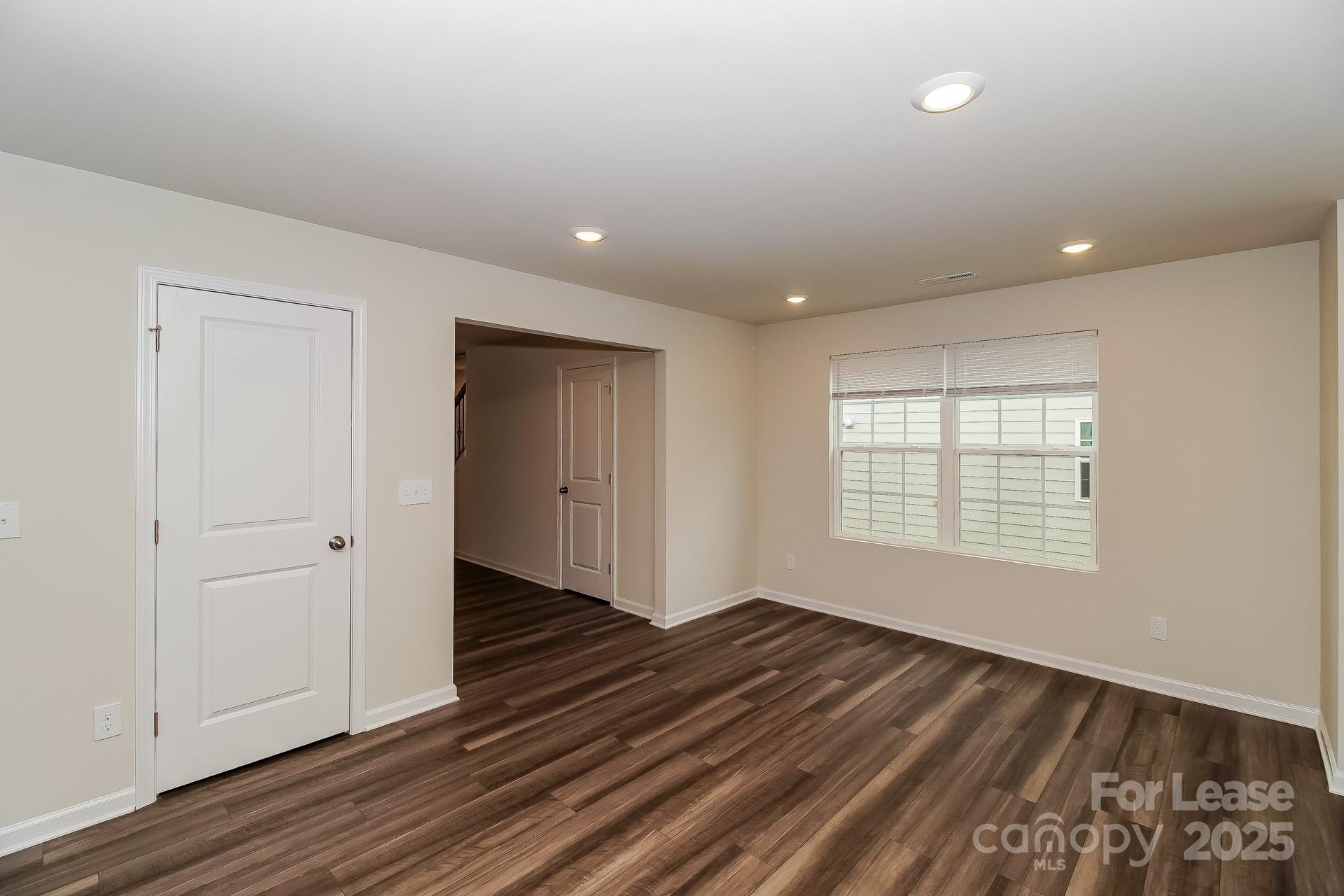131 Arden Court Troutman, NC 28166 - Photo 7 of 23 a view of an empty room with wooden floor and a window