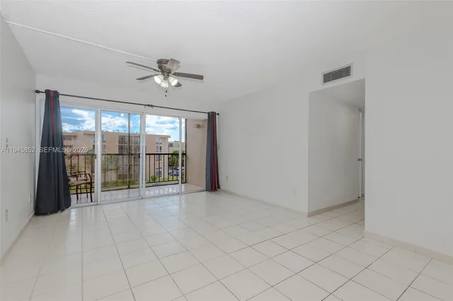 an empty room with chandelier fan and windows
