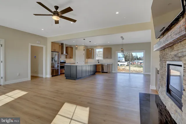 a view of a living room with wooden floor and a fireplace