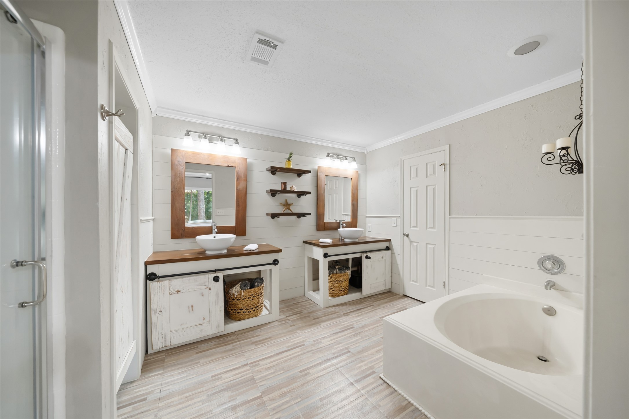 3 East Stony Bridge Circle Spring, TX 77381 - Photo 28 of 42 This primary en suite bathroom features modern farmhouse design elements, including dual vessel sinks on extended countertops, a large soaking tub, and a separate walk-in shower. The functional layout includes built-in storage cabinetry and direct access to the walk-in closet.