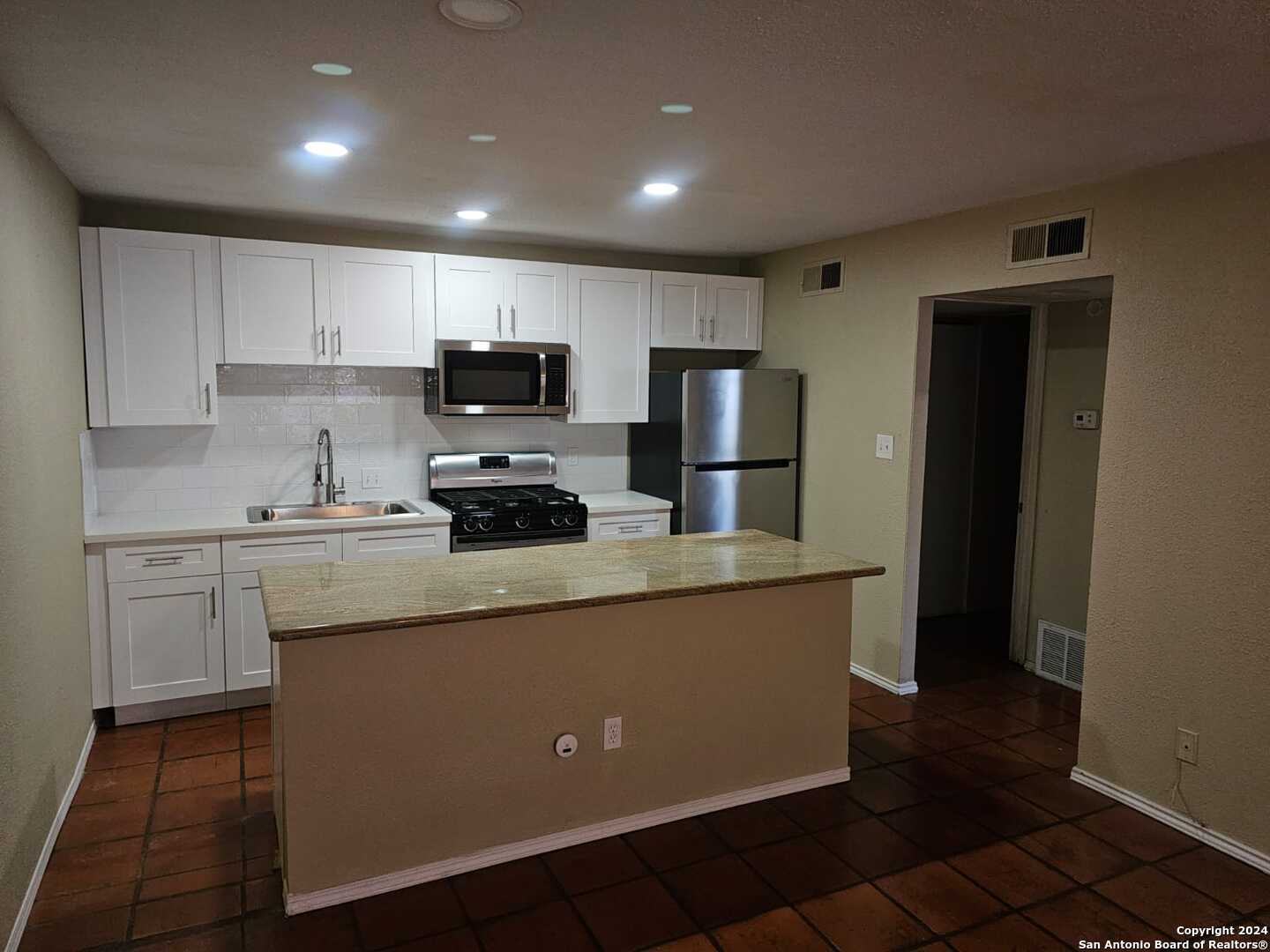 a kitchen with kitchen island white cabinets and refrigerator