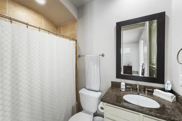 a bathroom with a granite countertop sink toilet and a mirror