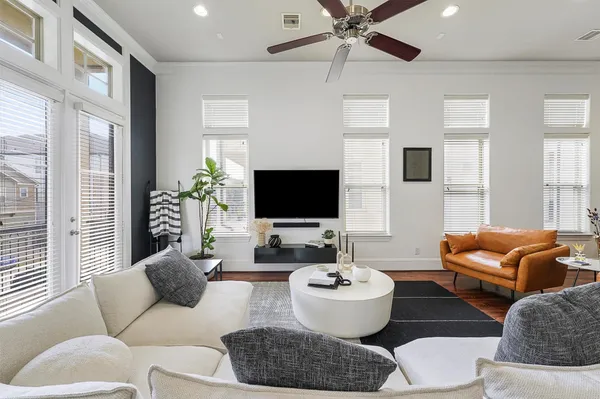 a living room with furniture a flat screen tv and a large window