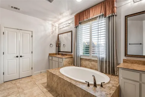 a bathroom with a granite countertop tub sink and mirror